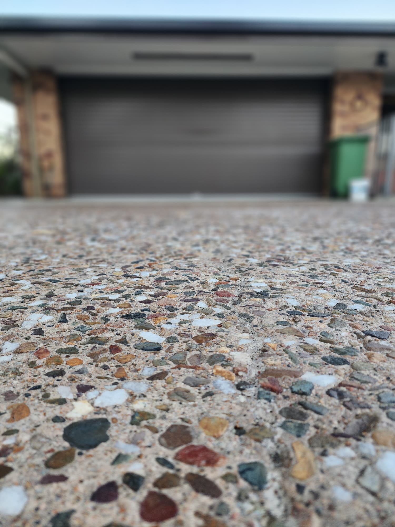 An exposed concrete driveway leading to a garage door, showcasing a clean and modern residential entrance.
