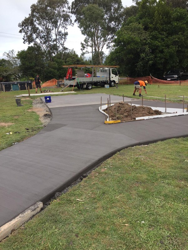 A concrete driveway is being poured in a park, creating a new path for visitors to enjoy the outdoor space.